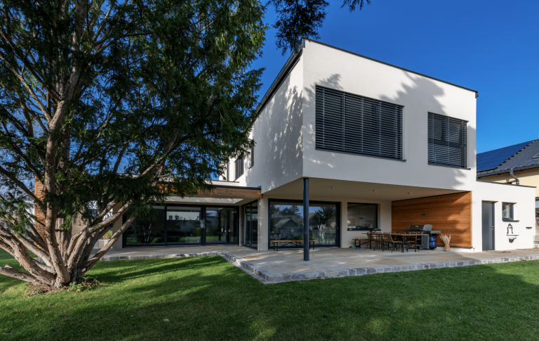 Einfamilienhaus mit Flachdach, überdachter Terrasse, Garten und Garage von AL Architekt ZT.