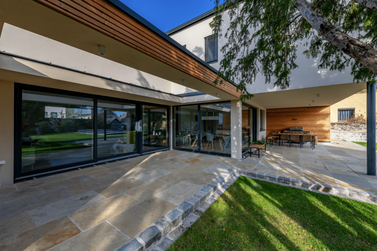 Einfamilienhaus mit überdachter Terrasse und Außenfliesen von AL Architekt ZT.