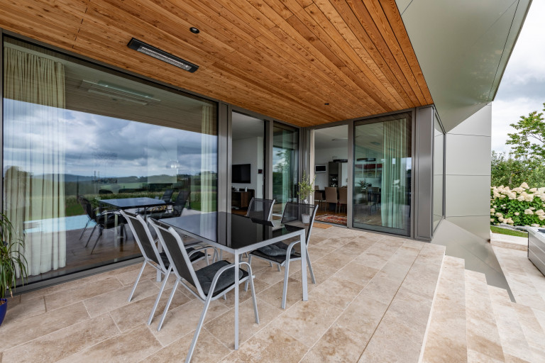 Integrierte Steinboden-Terrasse mit Holzdecke und breitem Stiegenabgang in den Garten von AL Architekt.