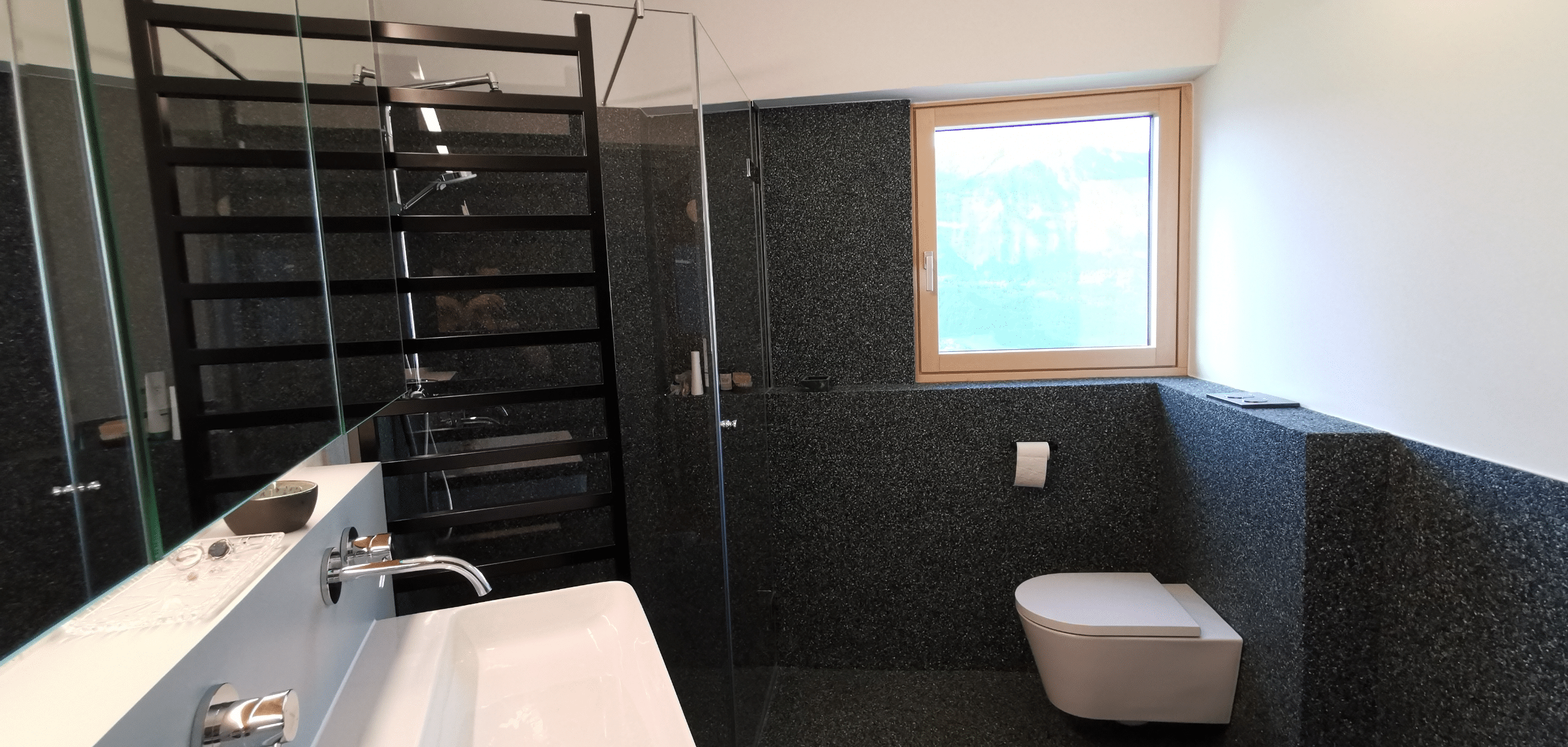stoneCARPET präsentiert einen schwarzen Natursteinbelag als Verkleidung der Wände in einem modernen Badezimmer mit barrierefreier Dusche.