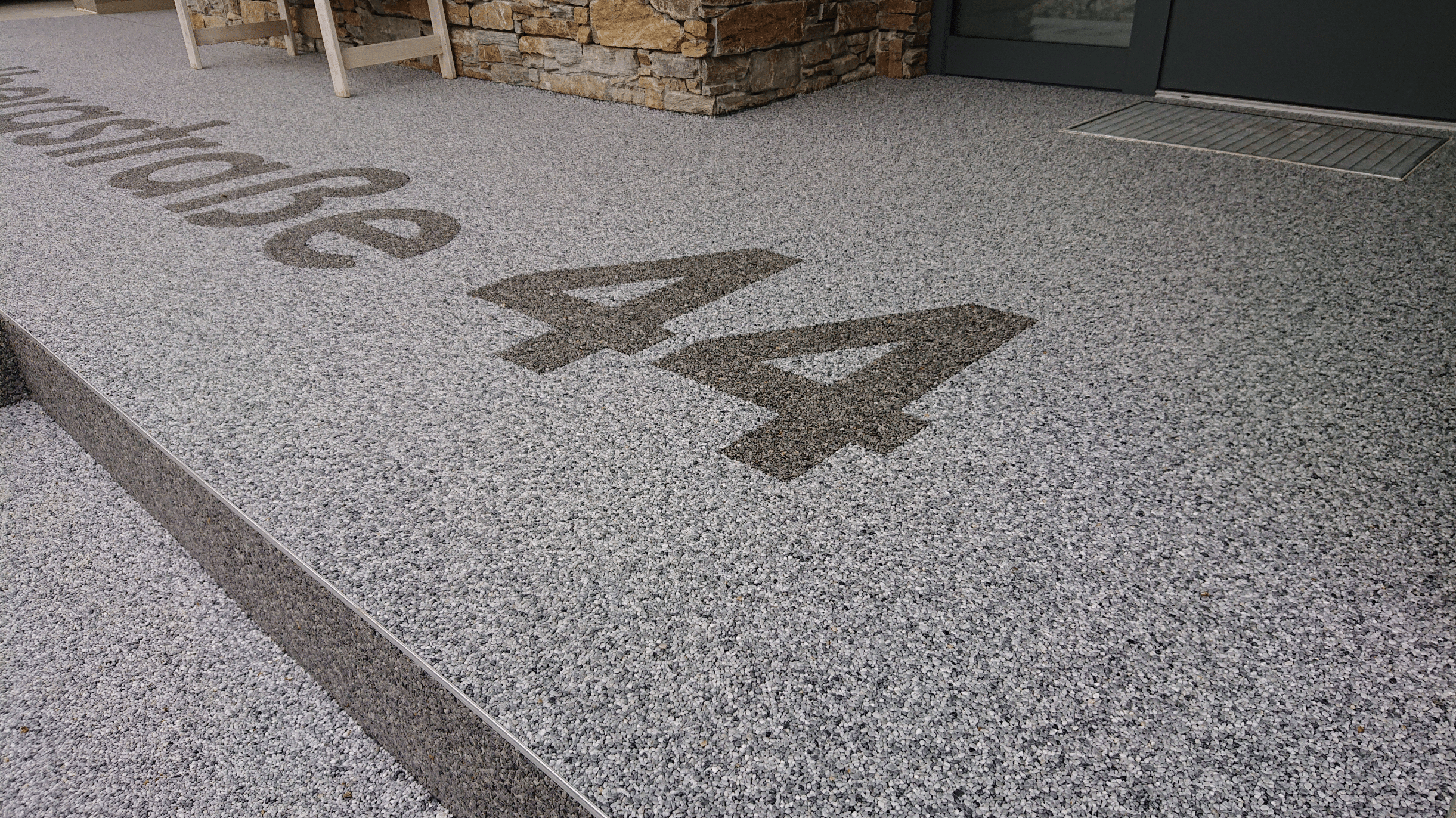 stoneCARPET präsentiert einen hellen Natusteinteppich im Eingangsbereich eines Hauses, in dem die Adresse mit einem dunkleren Teppich geschrieben wurde.