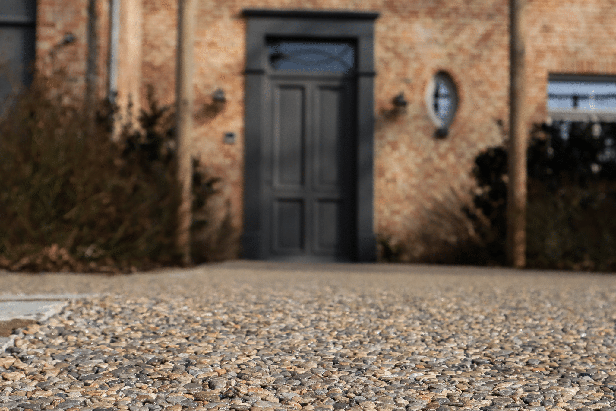 stoneCARPET präsentiert einen rötlichen Natursteinteppich im Eingangsbereich eines Hauses mit schwarzer Eingangstüre.