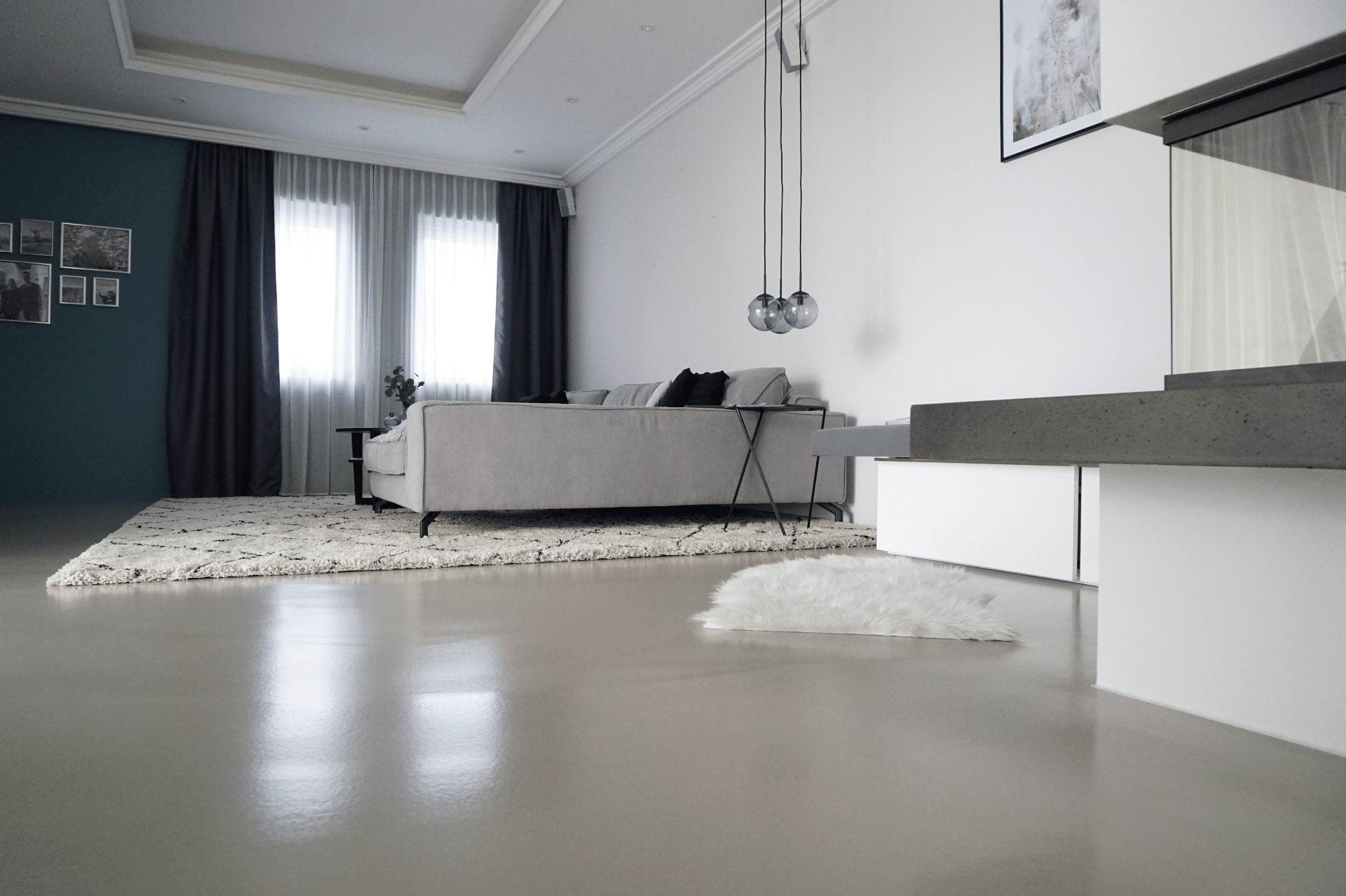 ARDEX zeigt ein Wohnzimmer mit einer großen, hellgrauen Couch auf einem hochflorigem Teppich, mit großen Fenstern, weissen Vorhängen und hellem Boden von panDOMO.
