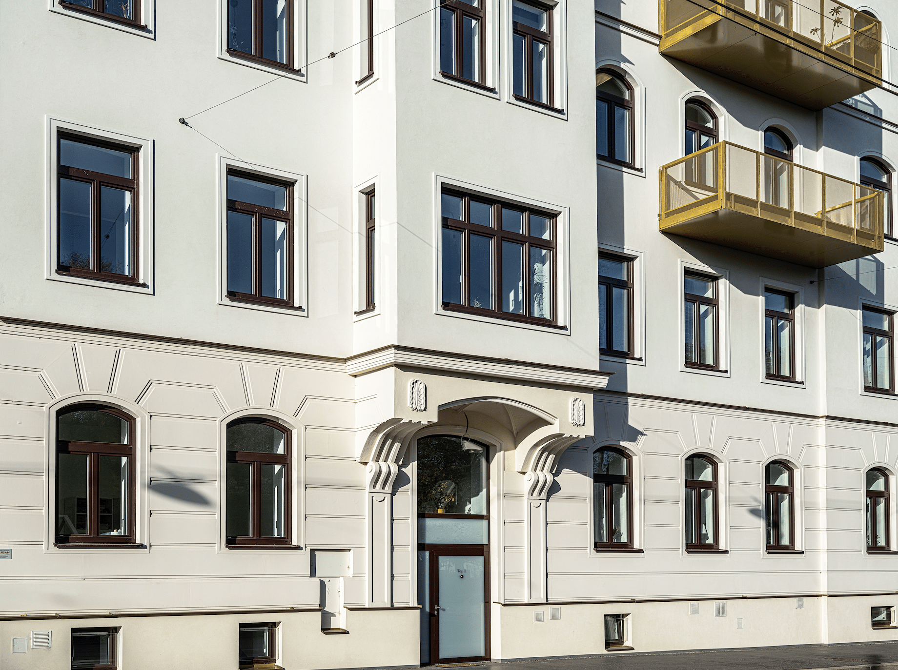 Ein schönes Gebäude mit sanierten Fenstern mit Holzrahmen und neuer Dämmung von Austrotherm und goldenen Ballkonen.