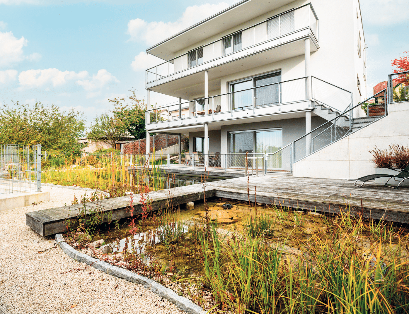 Bad Zeller zeigt ein mehrstöckiges weißes Haus mit kleinem Teich und Pool, einem Steg und schöner Bepflanzung davor.