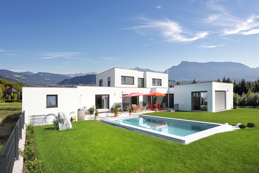 Bad Zeller zeigt ein weißes, modernes Haus mit Terrasse, Pool und großem Garten.