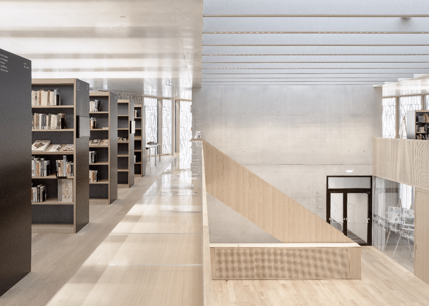 Treppenaufgang der Stadtbibliothek Dornbirn mit Materialmix aus Beton und Holz.
