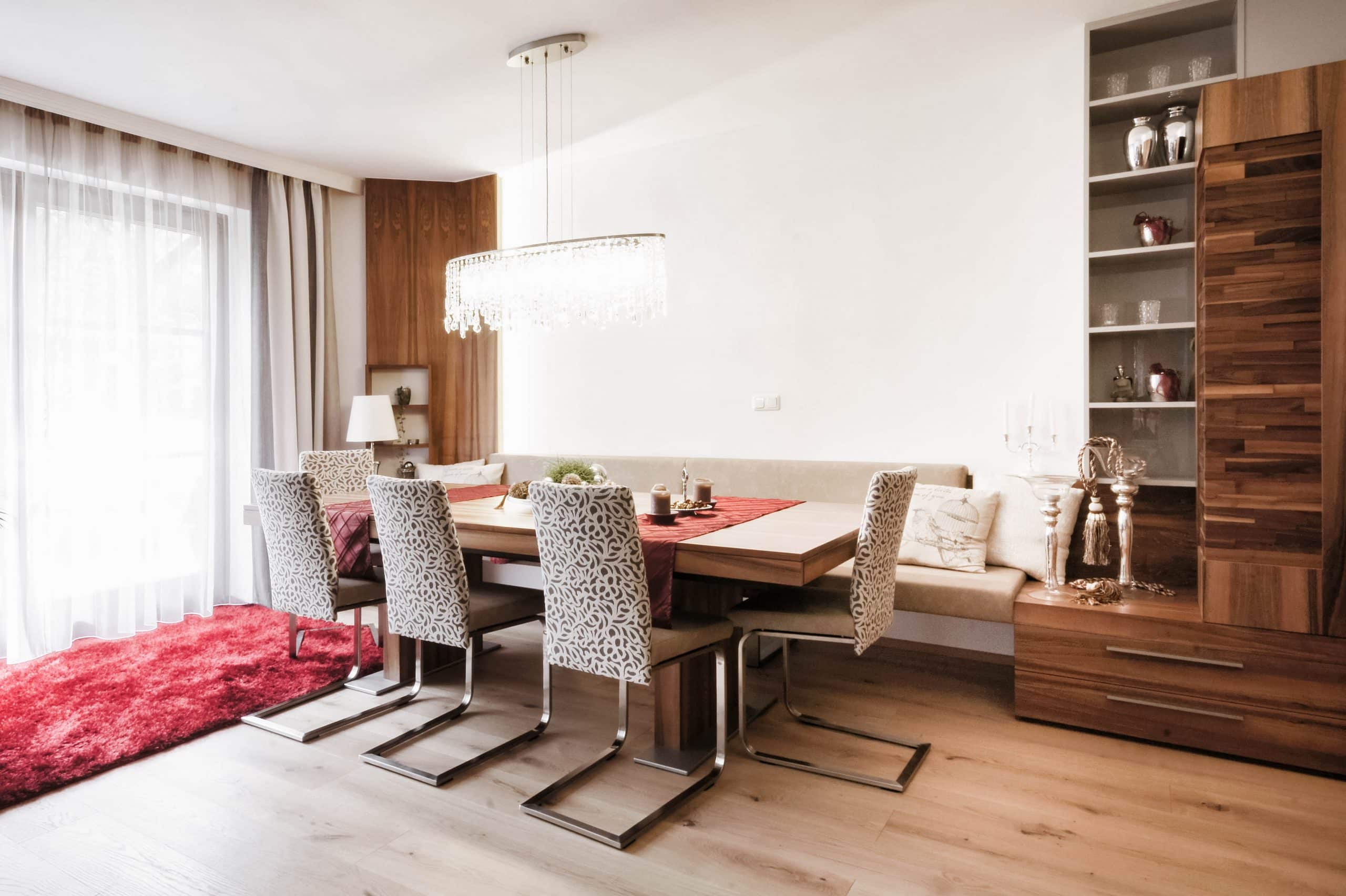 Offenes Wohn-/Esszimmer mit ausziehbarem Holztisch, Schwingsesseln und einer Bank mit hellem Bezug, konzipiert, gefertigt und eingebaut von der Tischlerei Böhm Möbel.