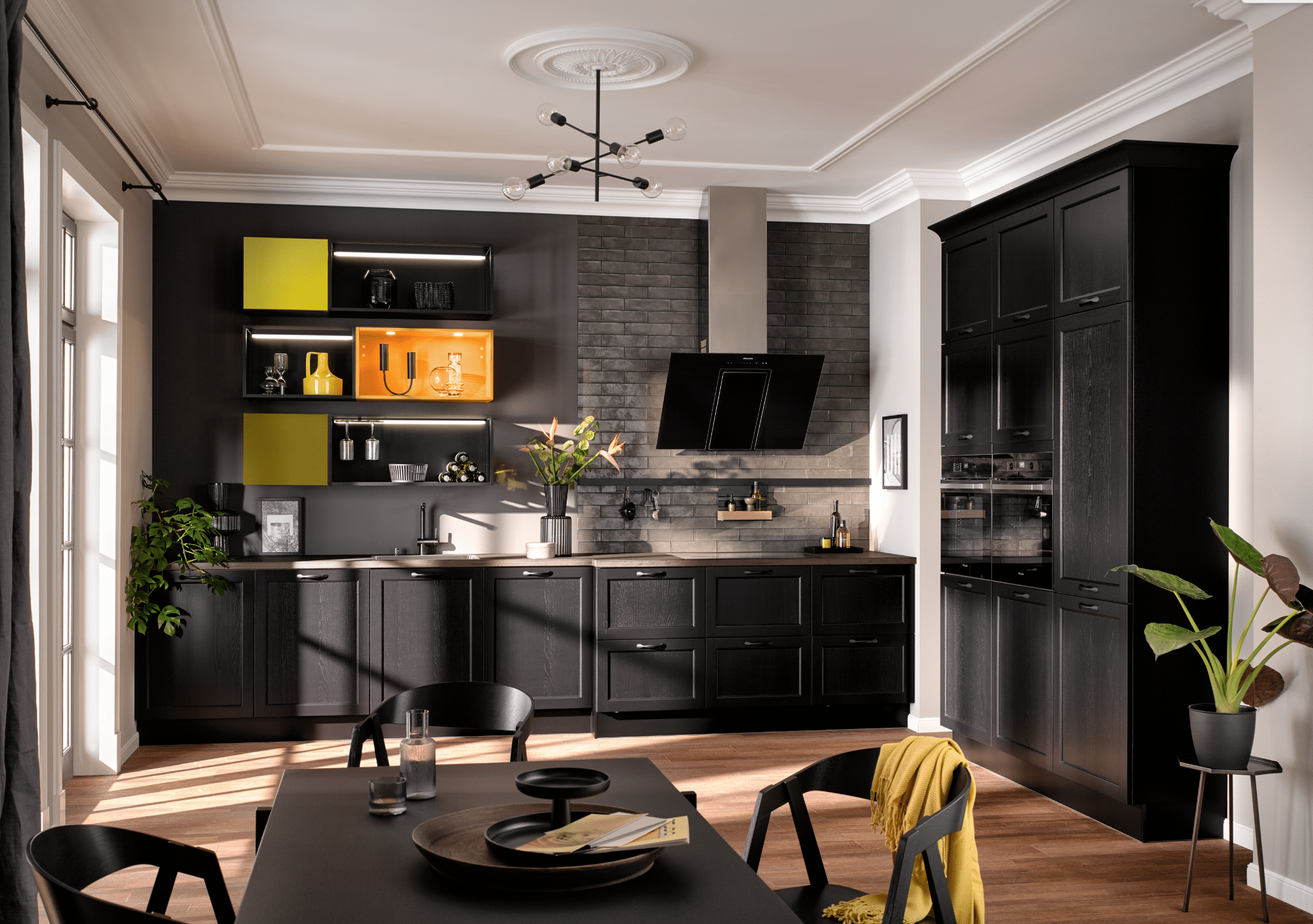 BÖHM MÖBEL zeigt eine schwarze Häcker Küche mit orangen und gelben Hängeschränken, Dunstabzug und Esstisch.