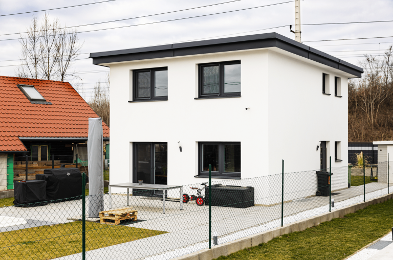 Einfamilienhaus mit Flachdach, weißem Putz und schwarzen Alufenstern von DIALOG Haus.