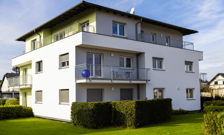 Mehrfamilienhaus mit Flachdach, Balkon und Garten von DIALOG Haus.