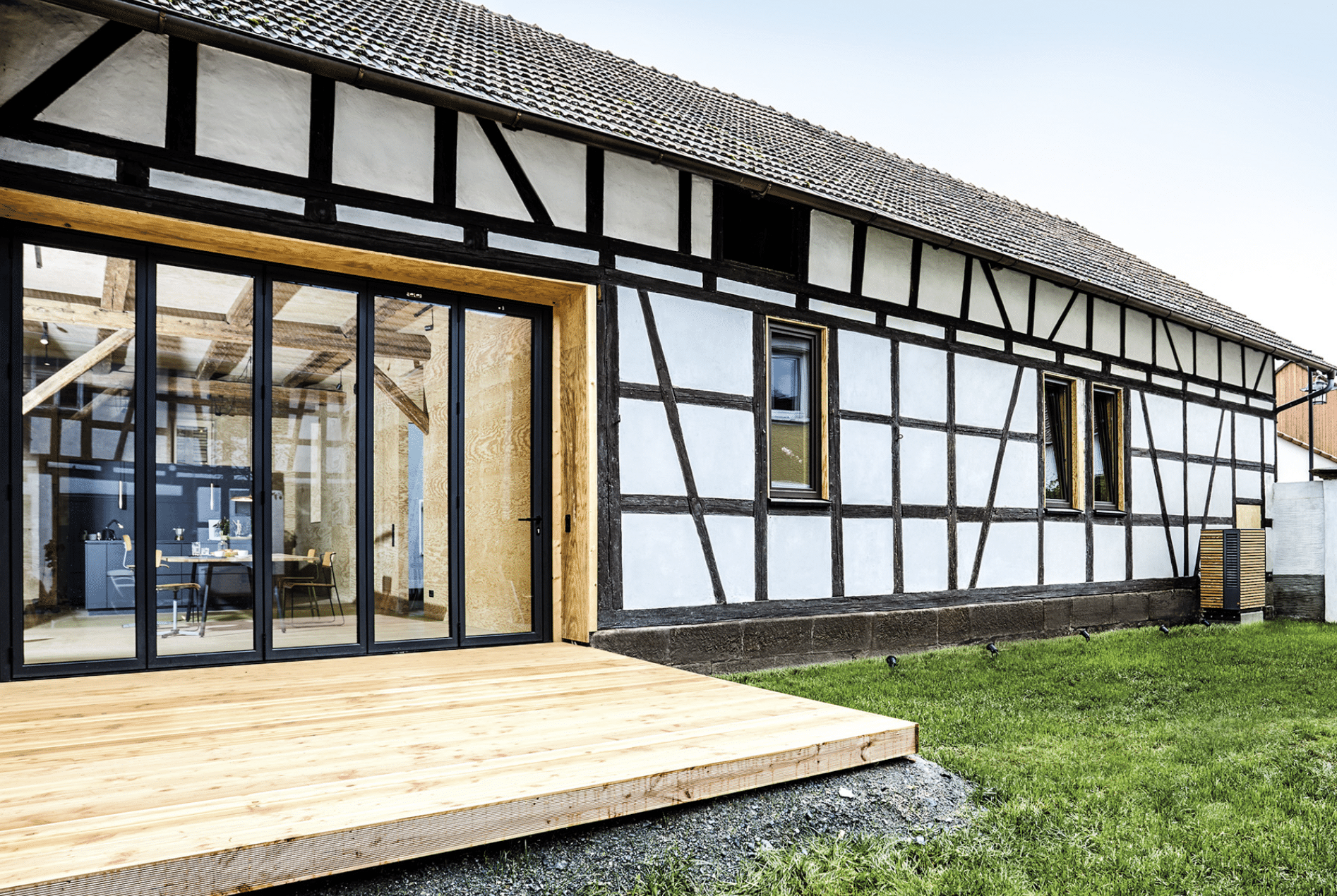 Dimplex zeigt eine Wärmepumpe mit Holzverkleidung im Außenbereich eines älteren Landhauses mit großer Terrasse.