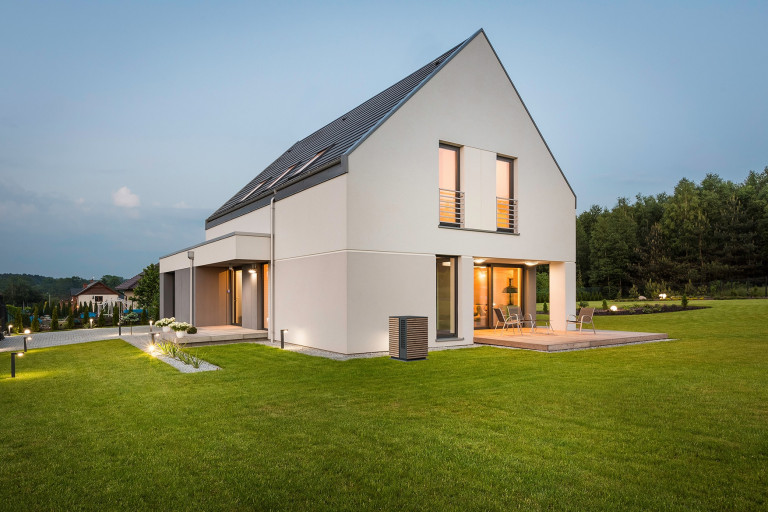 Wärmepumpen Außeneinheit in anthrazit und Holzverkleidung vor einem modernen Haus von Dimplex.