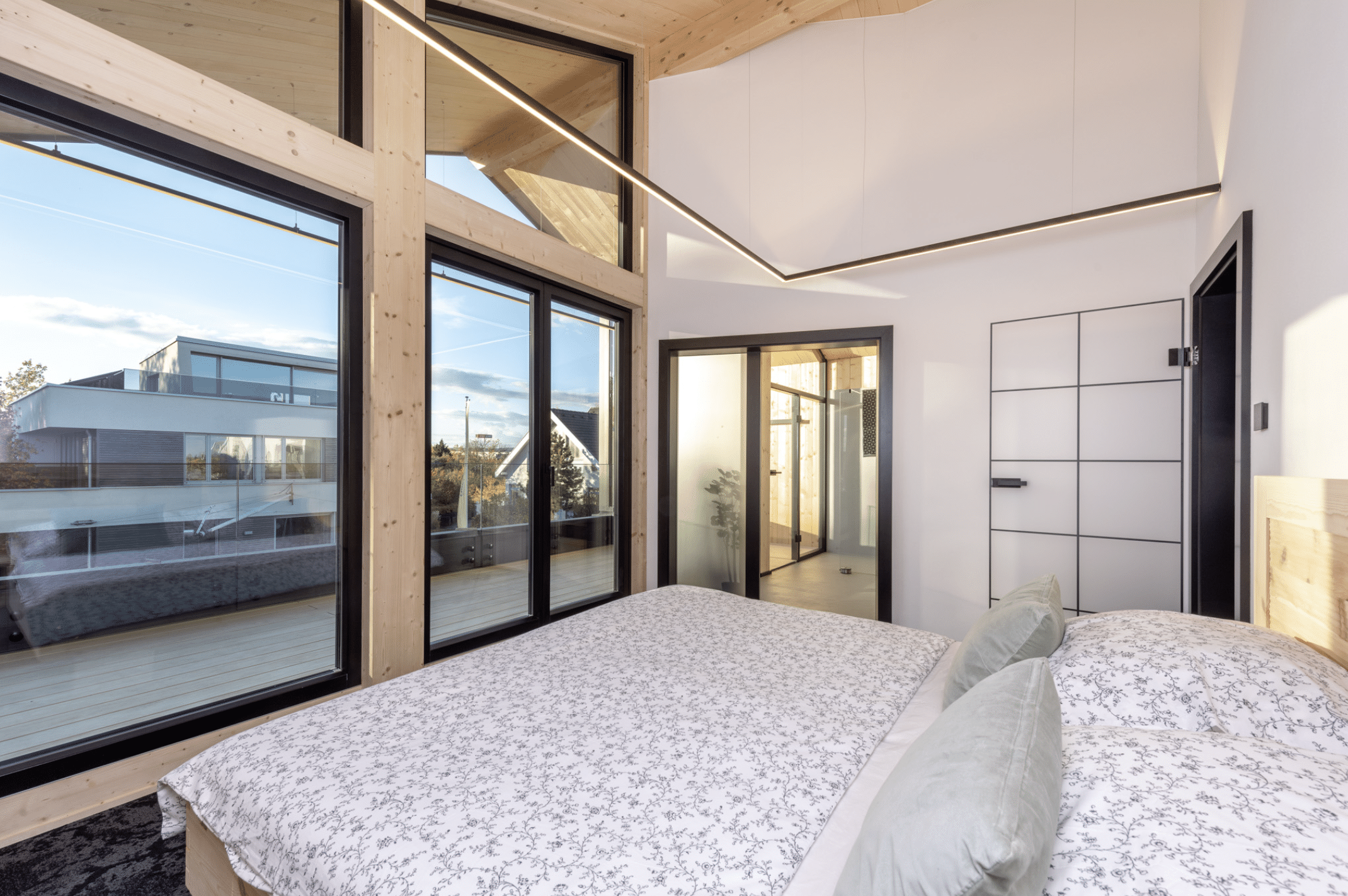 Erler Haus zeigt ein sehr helles Schlafzimmer mit hohen Decken, schwarzen Türrahmen, einer Lofttüre und Holzbalken.