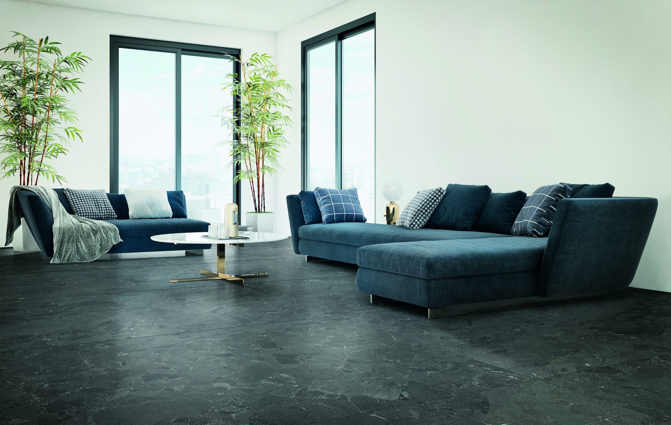 Fliesendorf zeigt ein mit blauen Sofas eingerichtets Wohnzimmer mit zwei hohen Fenstern und dunklem marmorierem Boden.
