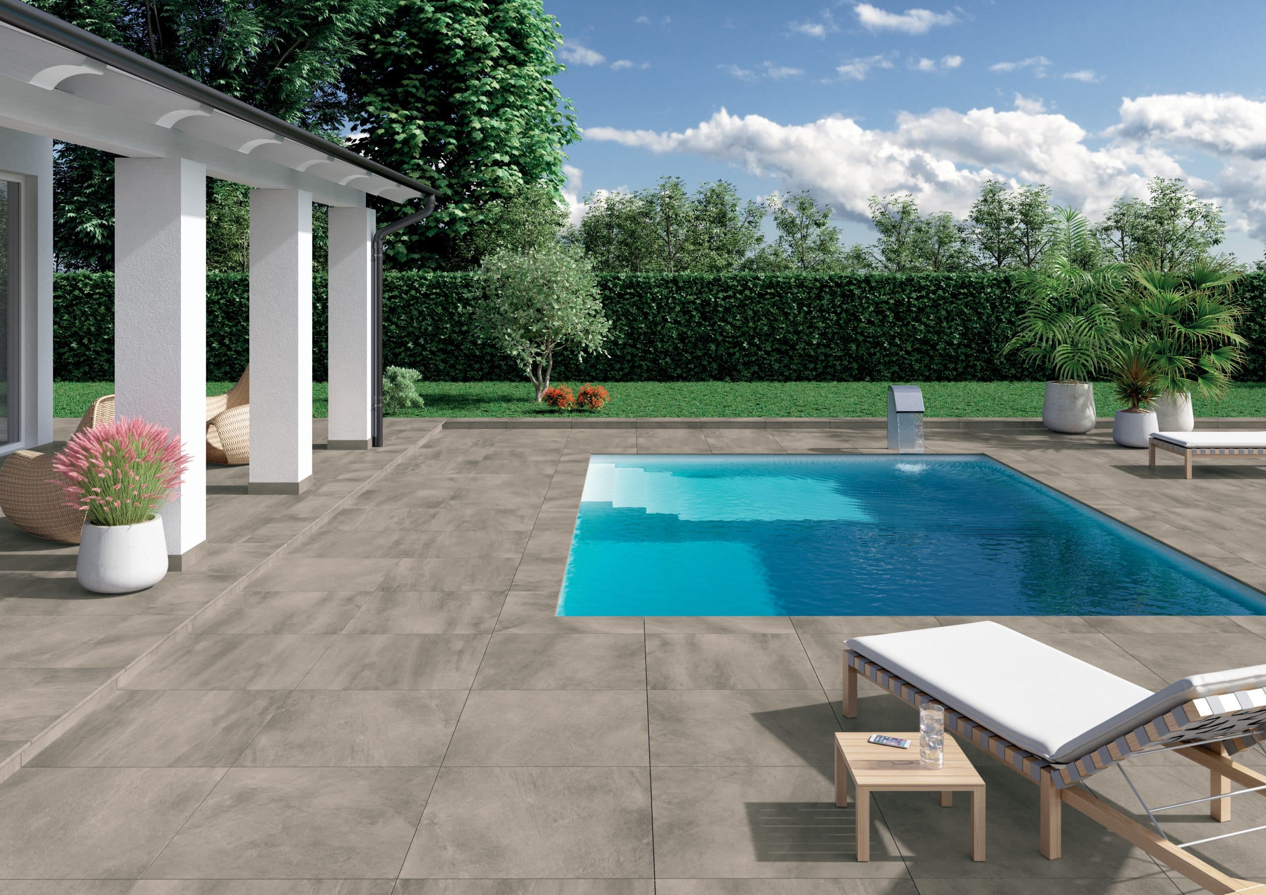 Fliesendorf zeigt eine große Außenanlage mit Pool, rundherum die großflächigen, grauen Fliesen in einem Garten, einer überdachte Terrasse in weiß.