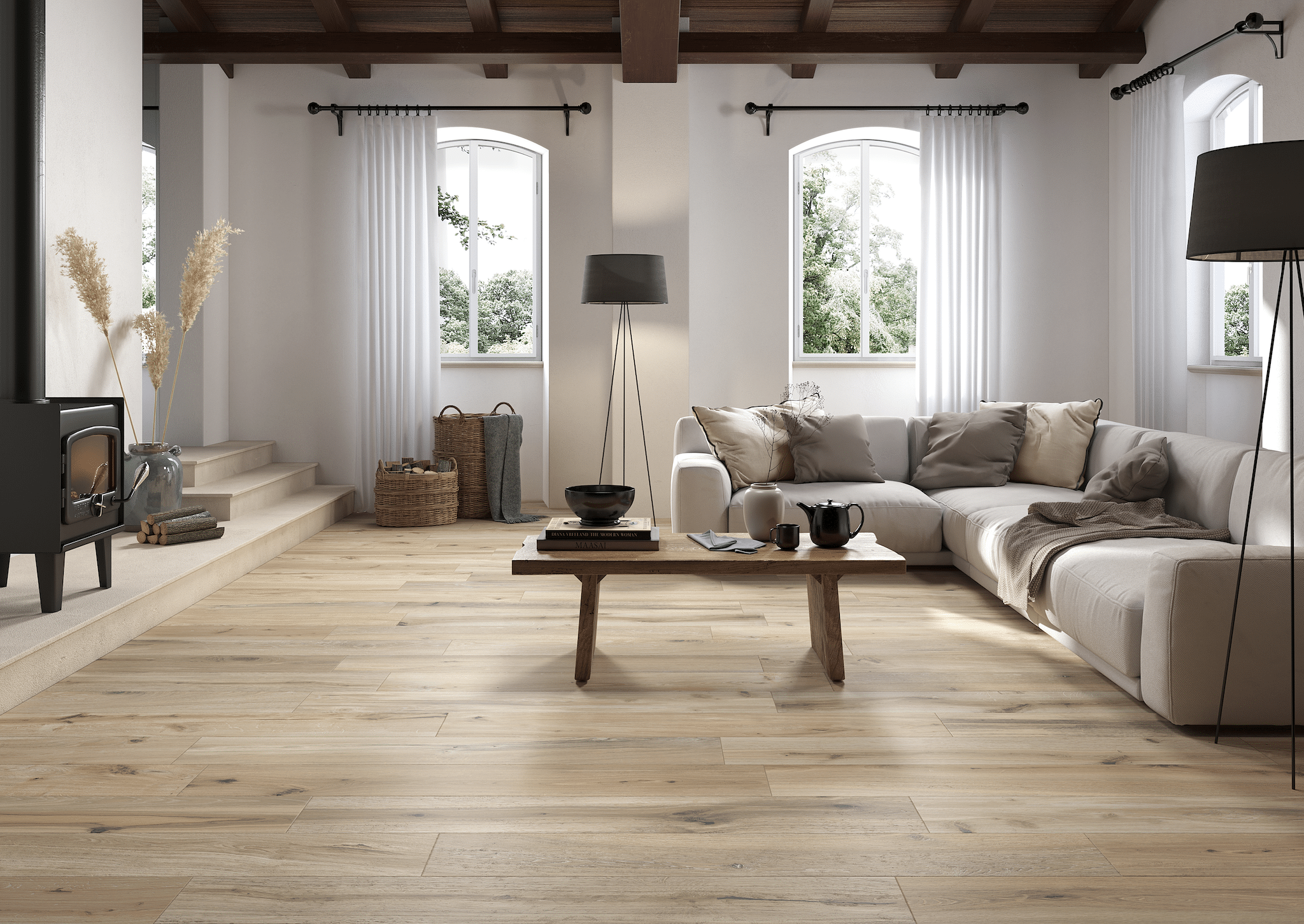 Fliesendorf zeigt ein sehr klassisches Wohnzimmer in beige, L-Couch mit verschiedenen Polstern, hohen,weißen Vorhängen, Couchtisch aus Holz und Fliesendielen im Holzlook.