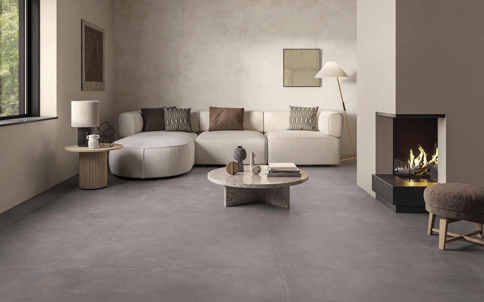 Fliesendorf zeigt ein Wohnzimmer in Naturtönen mit grauem Fliesenboden und heller Couchlandschaft mit einem schwarzen Kamin und rundem Beistelltisch aus Marmor.