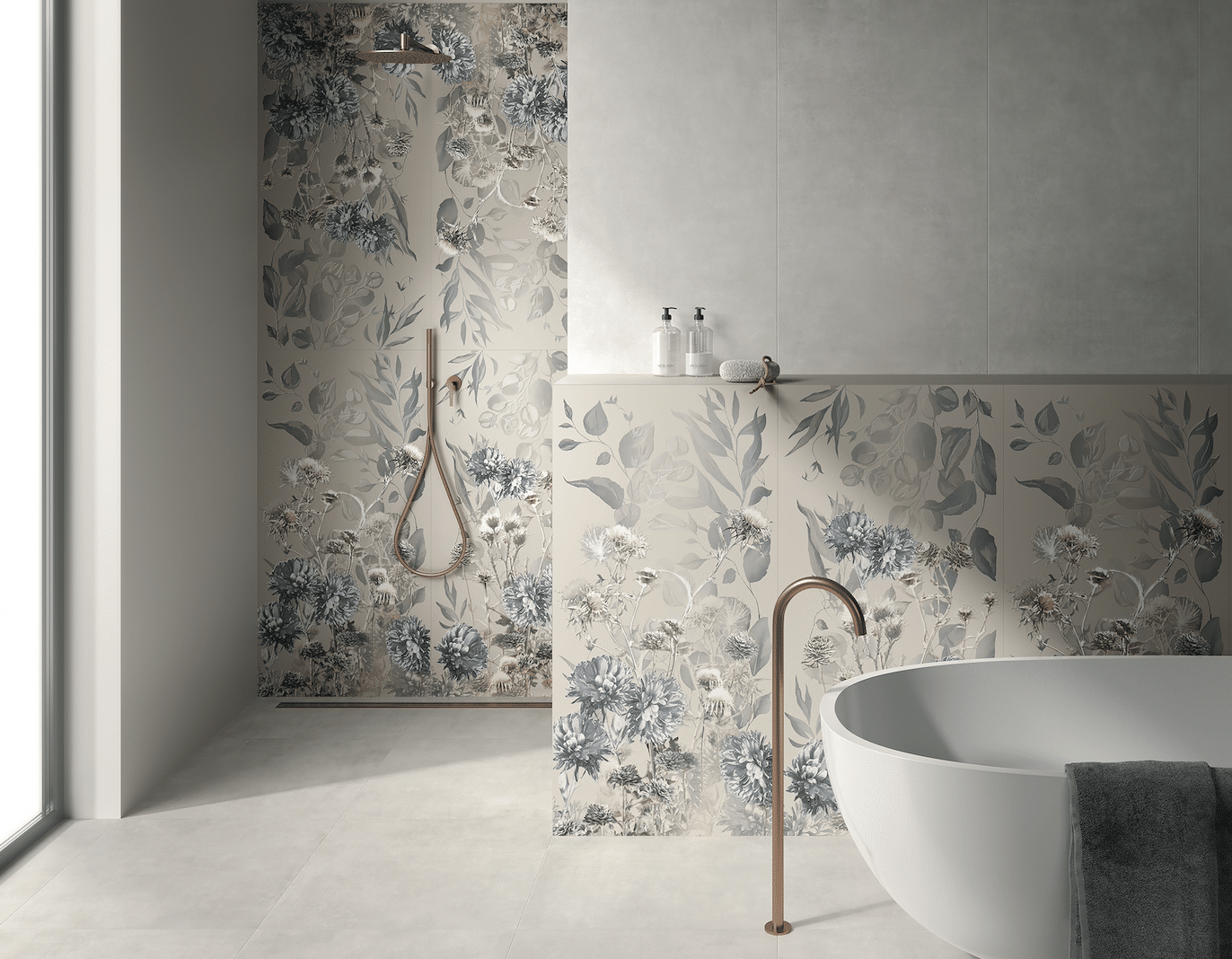 Fliesendorf zeigt ein Badezimmer mit hellem Fliesenboden und Wandfliesen mit floralem Muster in der offenen Dusche und hinter der freistehenden Badewanne mit goldenen Armaturen.