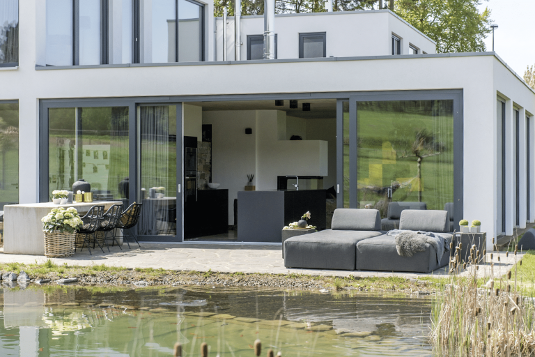 Außenansicht einer Terrasse eines Einfamilienhauses mit geöffneter Holz-Alu-Hebeschiebtür aus der Fusionline von Gaulhofer.