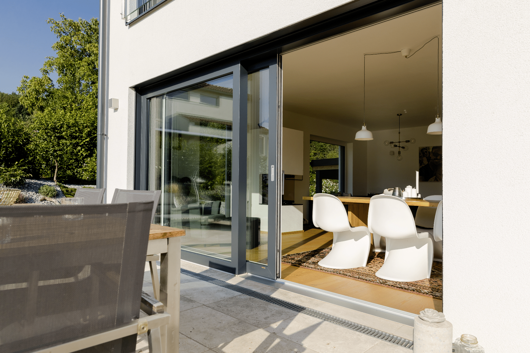 Terrasse mit Tisch und Stühlen und einer geöffneten Kunststoff-Alu-Hebeschiebetür aus der Energyline von Gaulhofer.