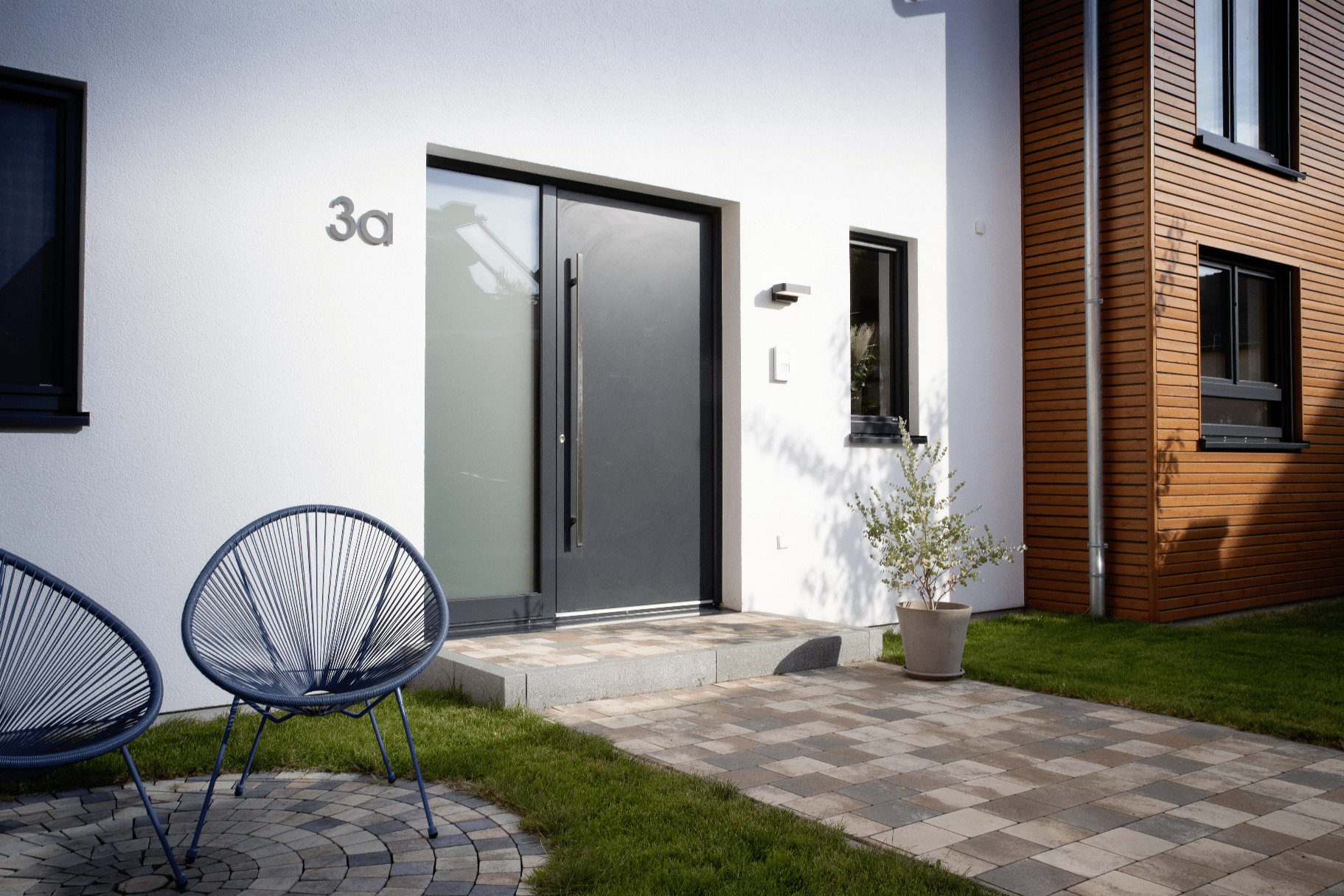 Anthrazit-farbene Alu-Haustüre mit vertikaler Griffstange und Glas-Seitenteil aus der Energyline von Gaulhofer.