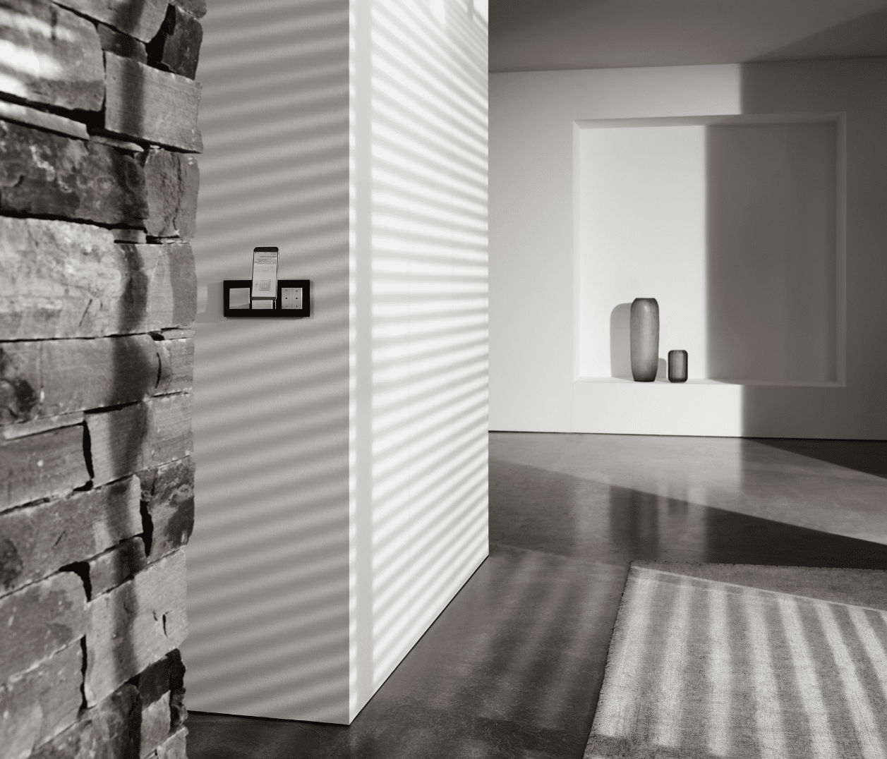Gira zeigt ein Wohnzimmer mit praktischer Smart Home Bedieneinheit, bestehend aus Schaltern und einer Docking Station für das Handy.