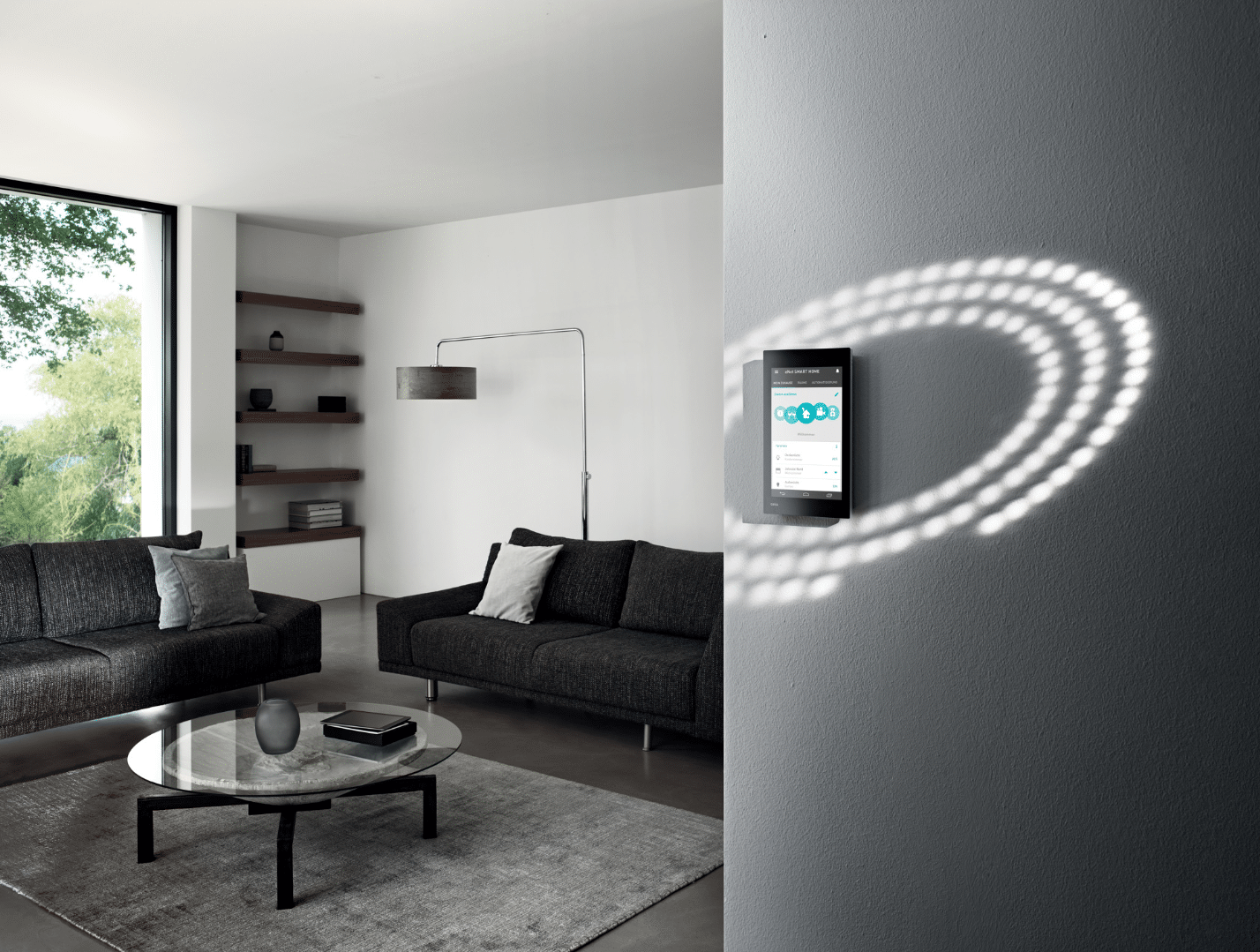 Gira zeigt das Wohnzimmer eines Smart Homes mit einer digitalen Bedieneinheit, in Augenhöhe an der Wand montiert.