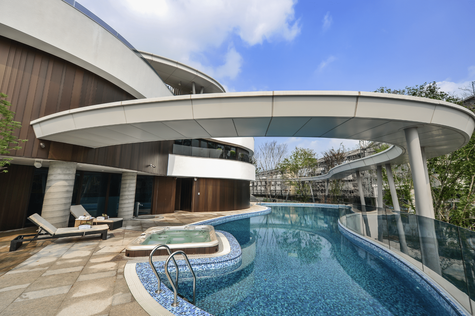 Moderne Flachdachvilla mit Holzfassade, geschwungener Terrasse und Pool mit integriertem Whirlpool von WOHNHAUS Grill & Ronacher aus dem Fotoshooting von LEICHT Küchen.