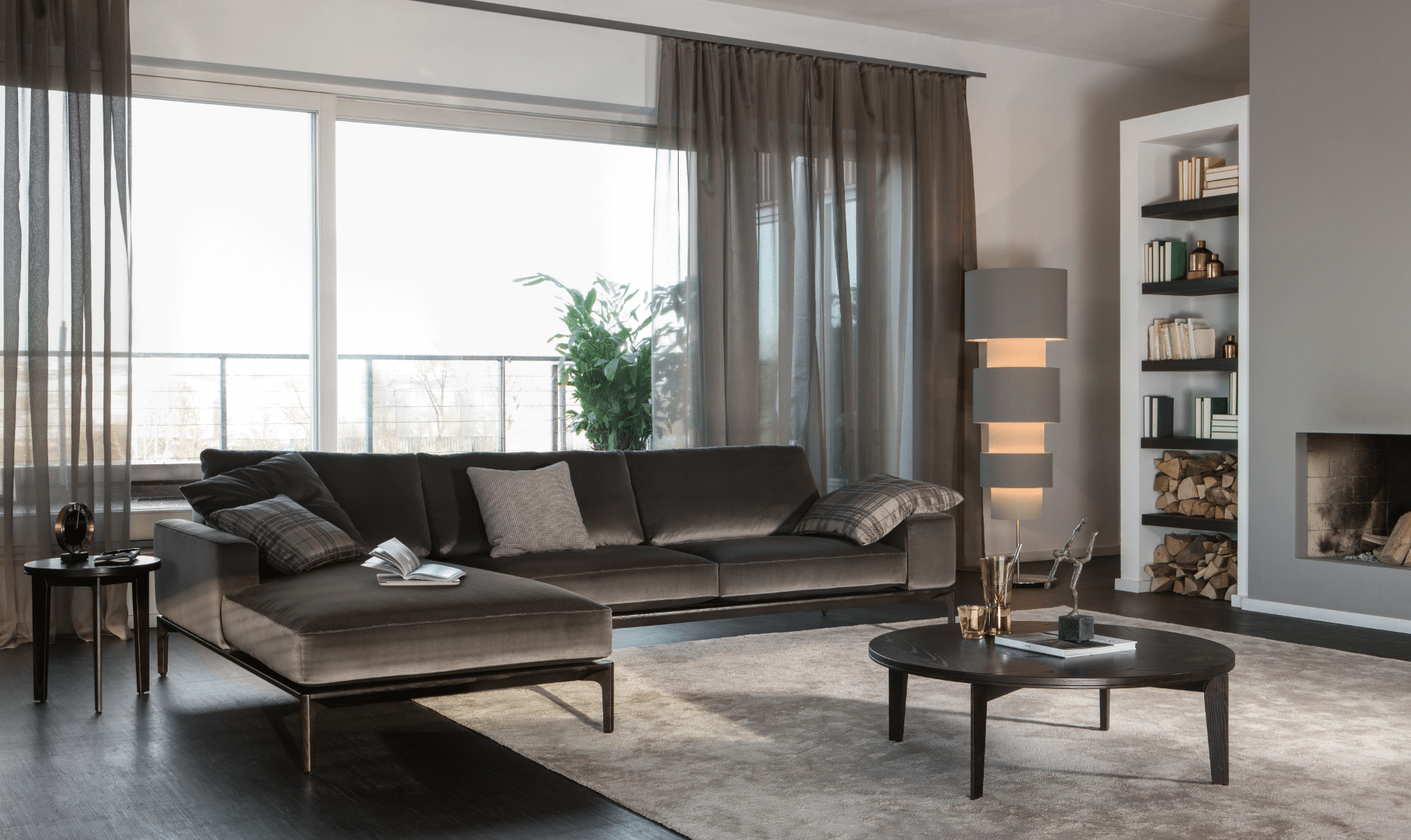 Elegantes Wohnzimmer mit dunkler Wohnlandschaft Eckelement Spirit, Stehlampe und Kamin aus dem Hause Bielefelder Werkstätten erhältlich bei WOHNHAUS Grill & Ronacher.