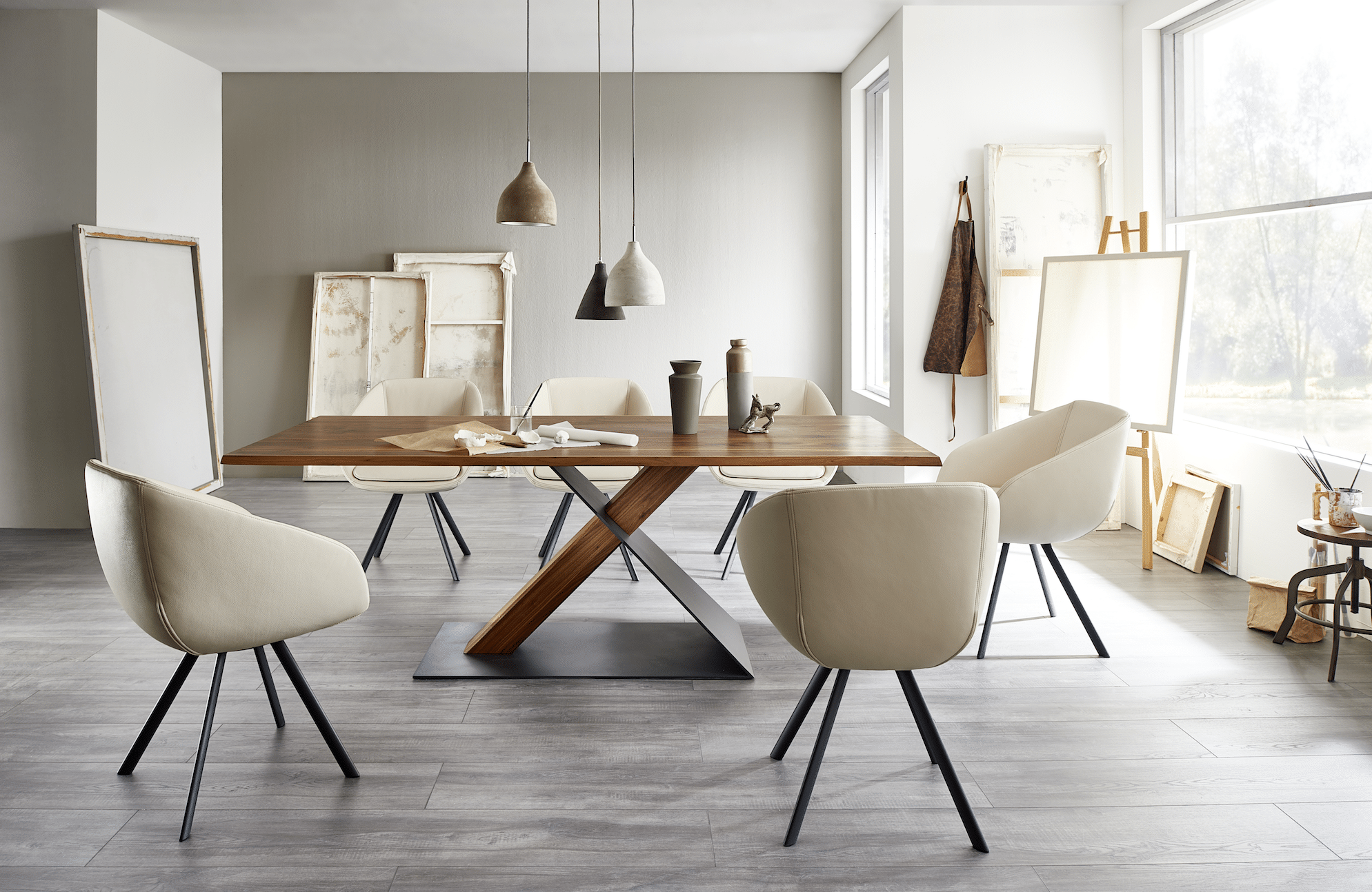 WOHNHAUS Grill & Ronacher zeigt ein Esszimmer mit cremefarbenen Stühlen und einem großen Tisch aus Holz und schwarzem Stahl von Wimmer Wohnkollektionen.