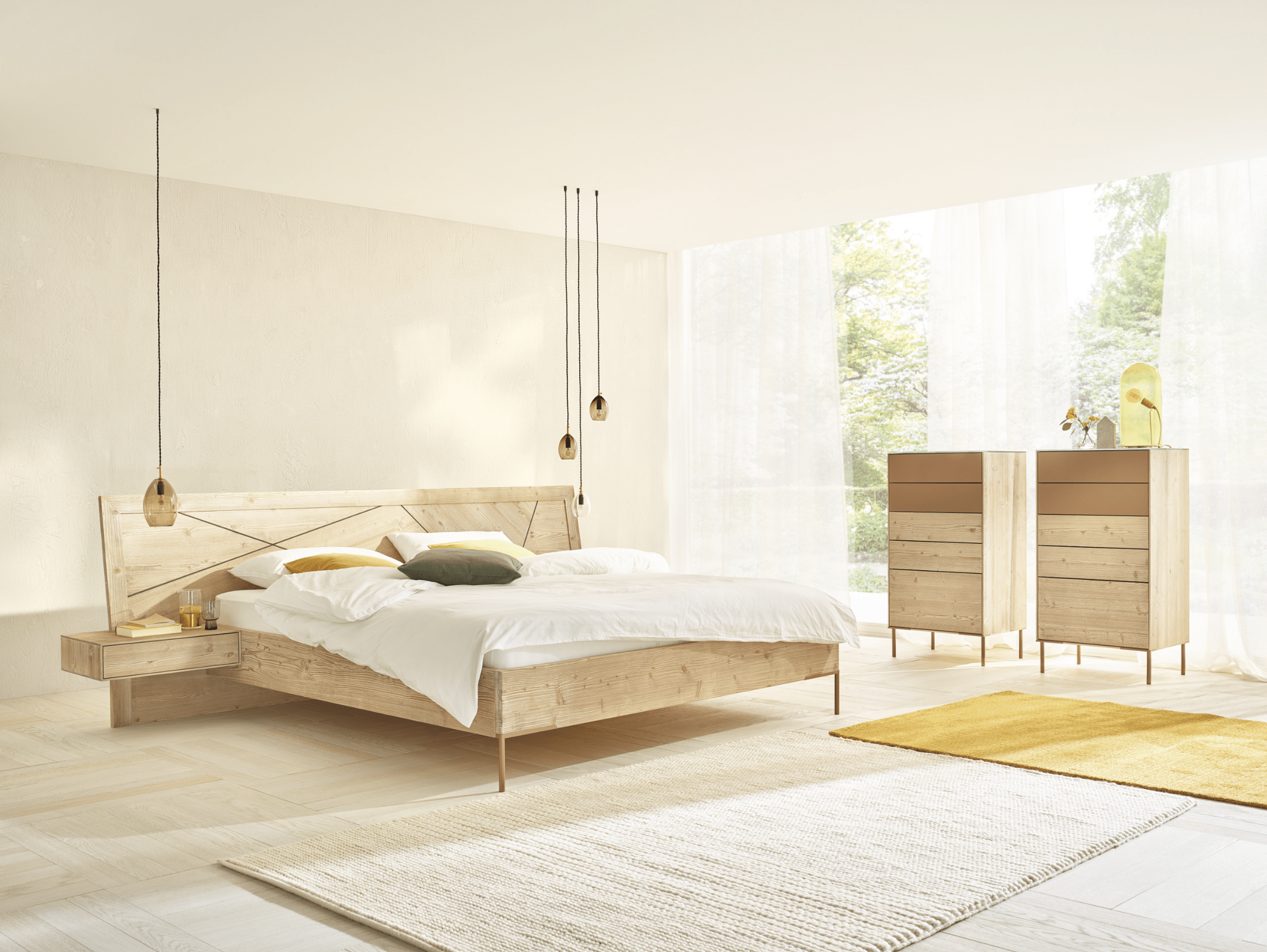 WOHNHAUS Grill & Ronacher zeigt ein modernes Schlafzimmer mit einem Doppelbett aus dem Holz der Bergfichte und dazupassenden Kommoden und freiliegendem Teppich.