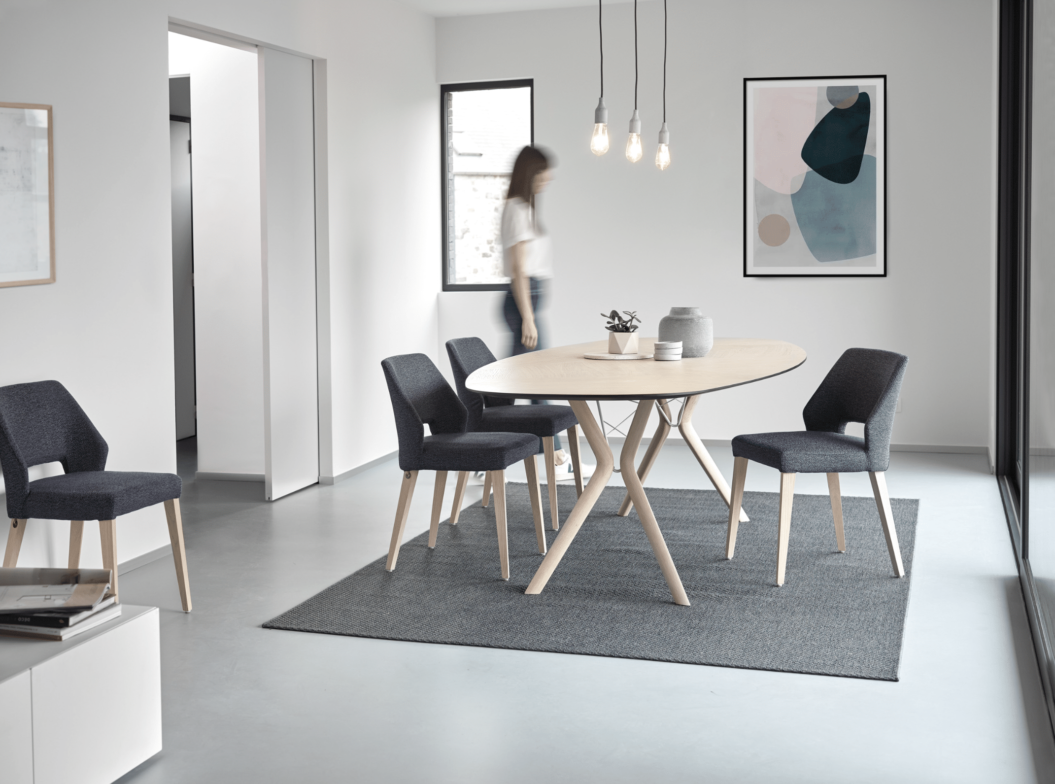 WOHNHAUS Grill & Ronacher zeigt eine Essgruppe von Mobitec Systems, bestehend aus einem Esstisch aus Holz und Stühlen mit Stoffbezug.