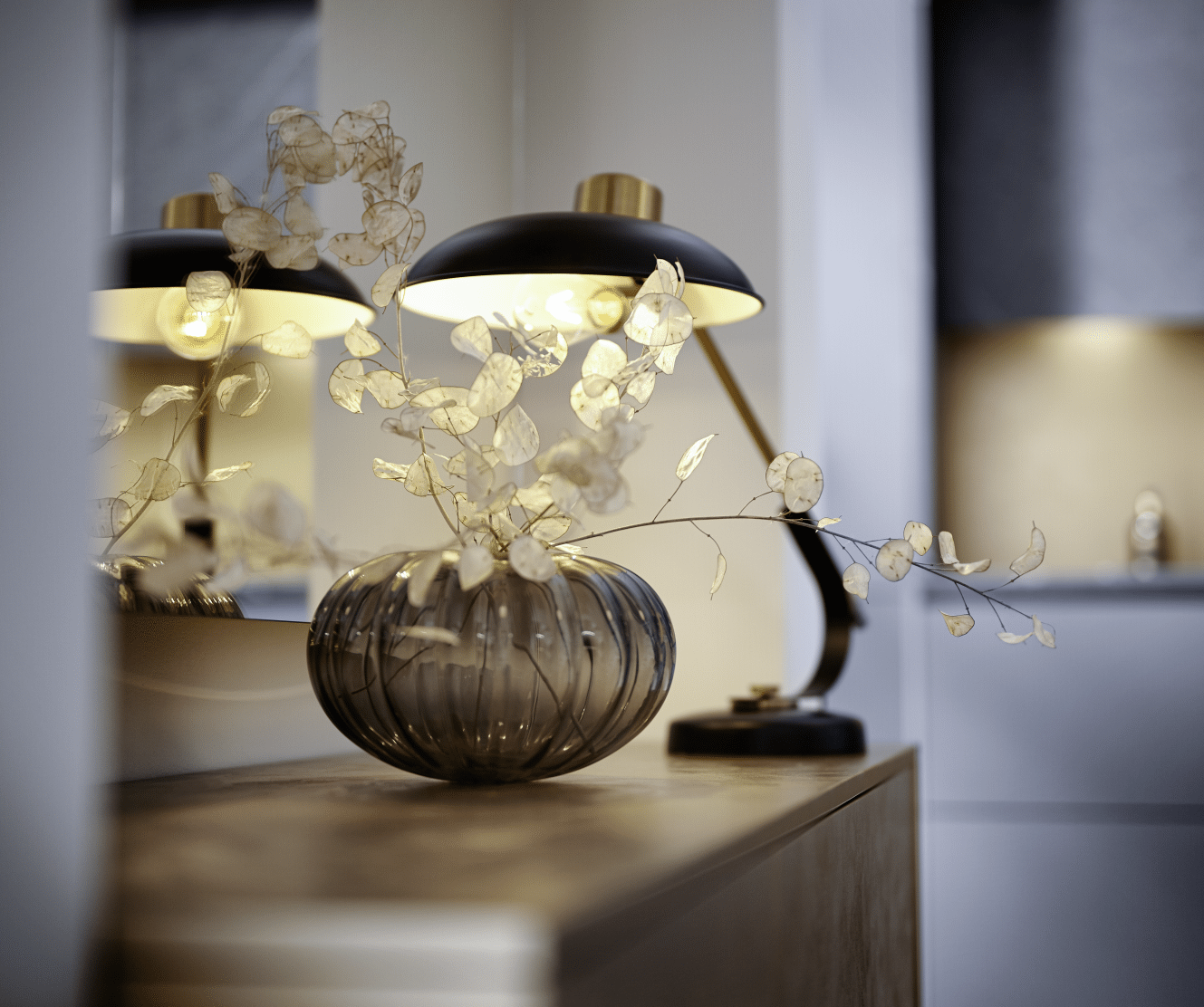 WOHNHAUS Grill & Ronacher zeigt eine Kommode mit schöner Lampe und Vase von Häcker Küchen.