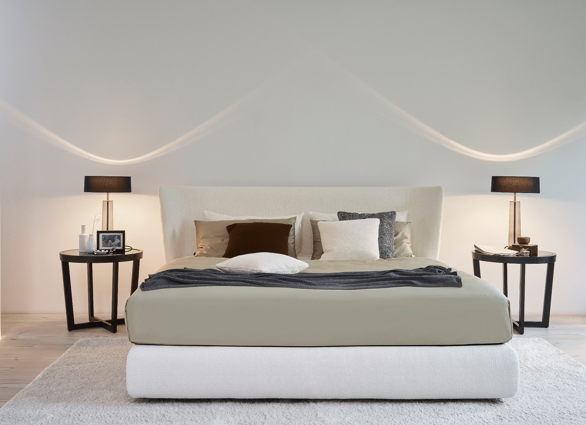 Grill & Ronacher zeigt ein Schlafzimmer mit Doppelbett in weiß, zwei Nachttischen, zwei Lampen und weißem Teppich von Bielefelder Werkstätten.