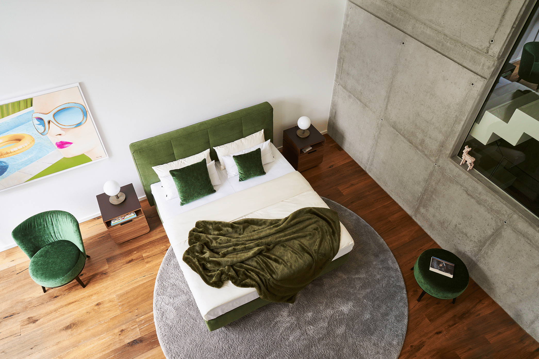 WOHNHAUS Grill & Ronacher zeigt ein modernes Schlafzimmer mit einem grünem Doppelbett, Ohrensessel und rundem, freiliegendem Teppich in der Vogelperspektive von Bielefelder Werkstätten.