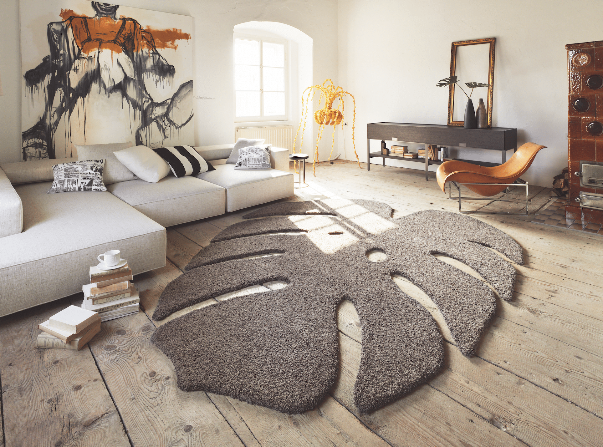 WOHNHAUS Grill & Ronacher zeigt ein modernes Wohnzimmer mit einem freiliegenden, braunen Teppich in der Form eines Blattes und einer hellen Couch von Landegger.