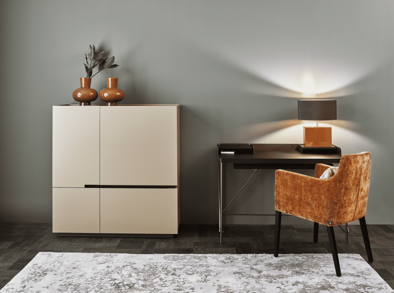 Wohnraum mit schwarzem Schreibtisch einem roten Polsterstuhl und einem grifflosen Schrank in Beige von Christine Kroencke Interior Design präsentier von Grill & Ronacher.