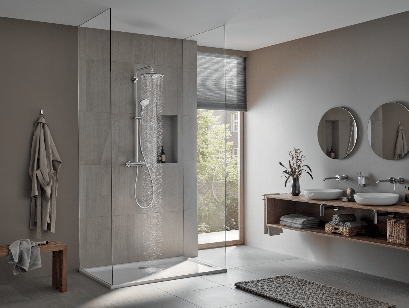 Grohe zeigt ein Badezimmer in verschiednen Grautönen, mit Doppelwaschbeckn, Walk-In Dusche und einer kleinen Fensterfläche.