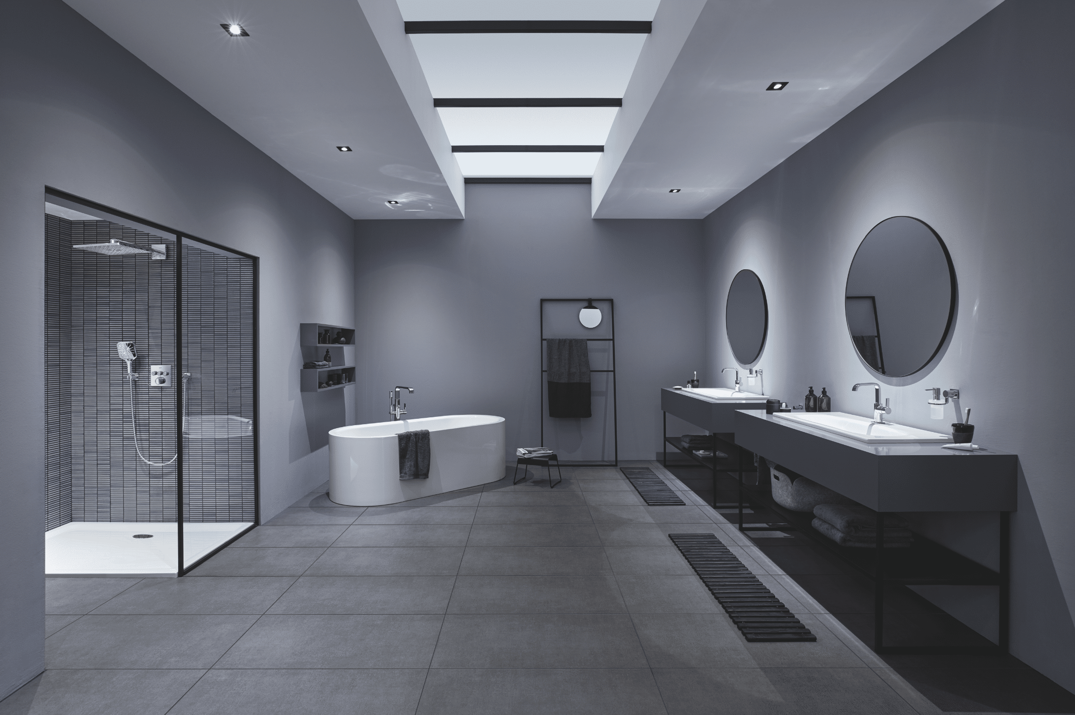 Grohe zeigt ein dunkelgraues Badezimmer mit freistehender Badewanne, Walk-In Dusche und zwei separaten Waschtischen.