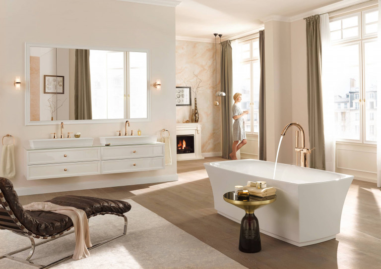 Edles Badezimmer mit gold glänzenden Armaturen von Grohe mit weißer freistehender Badewanne, weißem Doppel-Waschtisch mit Schubladenunterbau und Holzboden.