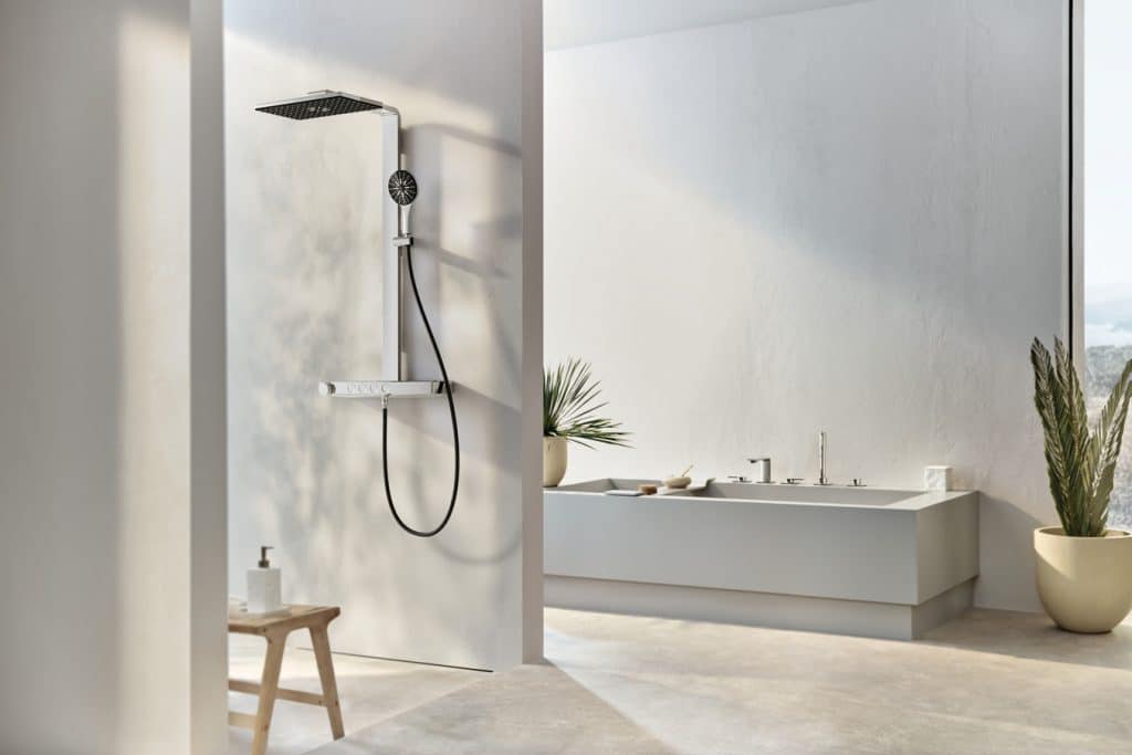 Badezimmer mit barrierefreier Duschnische mit Regendusche, Handbrause und einer Armatur mit Temperaturregelung in Chrome und einer rechteckigen Badewanne mit Brausestaub.