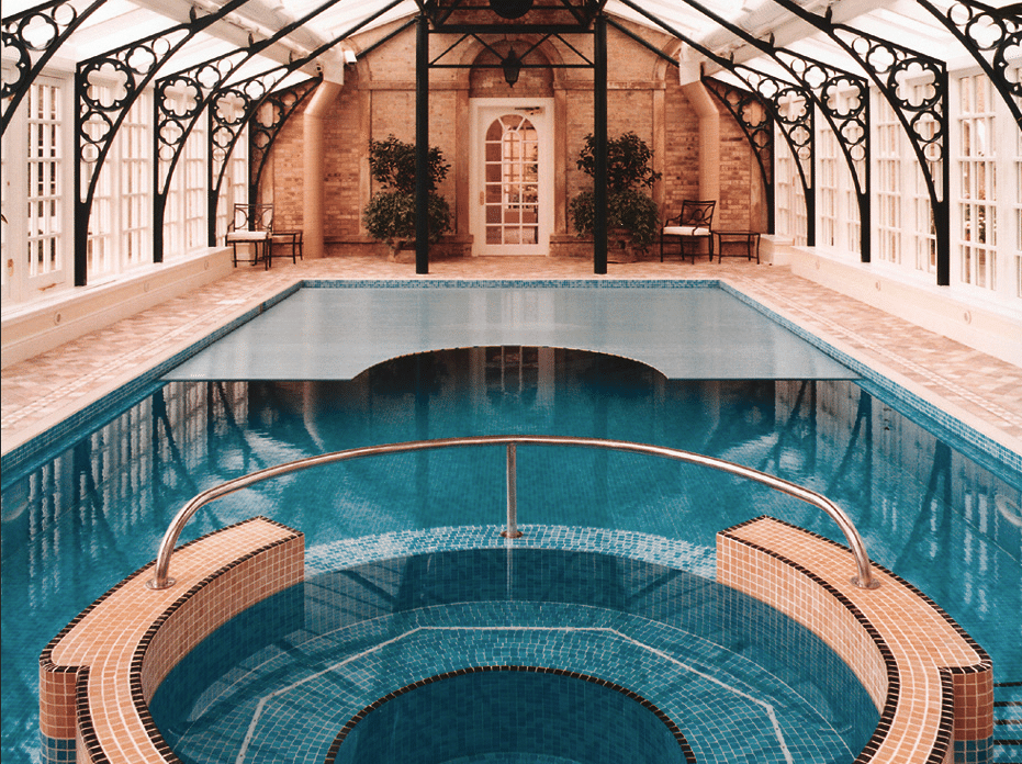 Hallenbad-Anbau im klassischen Stil mit großen Fenstern, Whirlpool und Indoor-Swimmingpool mit Poolüberdachung der Marke Grando, erhältlich bei Grossmann.