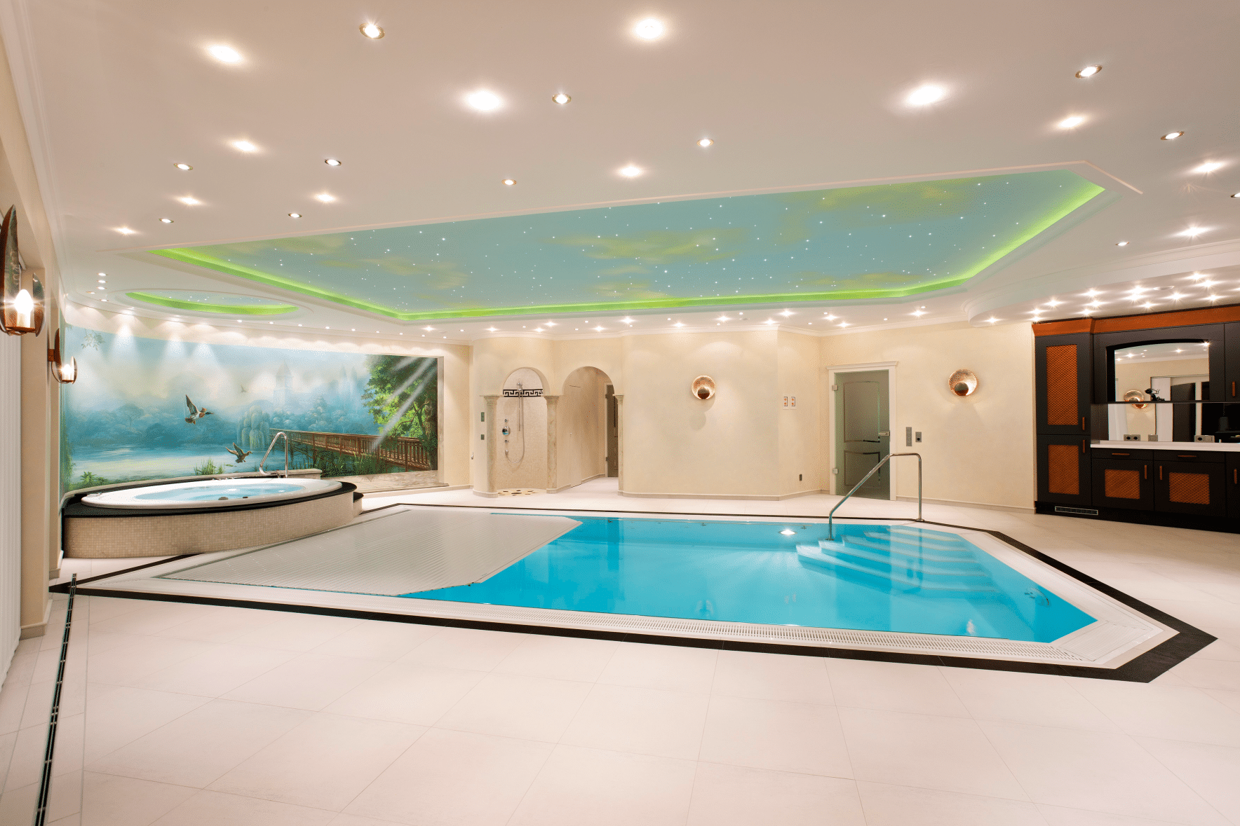 Hallenbad mit kunstvoller Wandmalerei, Dusche, Whirlpool und Indoor-Swimmingpool mit Poolüberdachung der Marke Grando, erhältlich bei Grossmann.