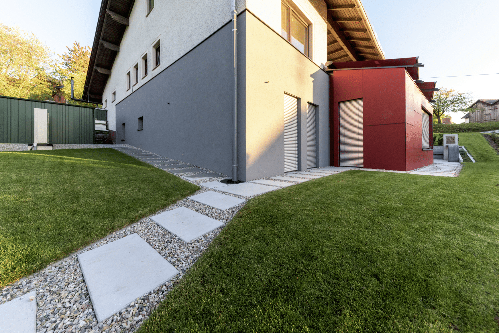 Haus mit Garten und Weg mit Steinplatten und Kies, angelegt von Gartengestalter Hablesreiter.