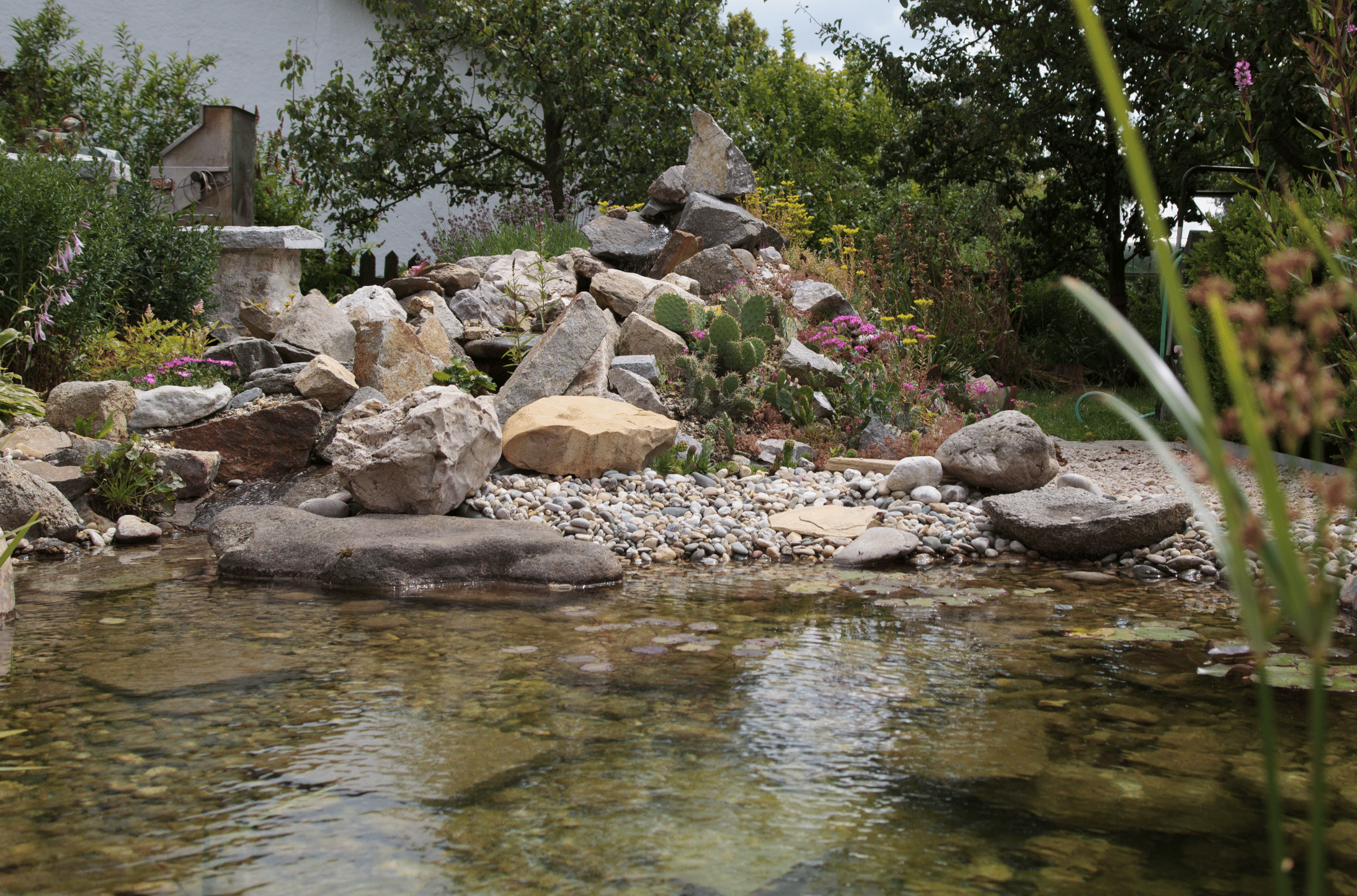 Hablesreiter legte in einem Teich eine kleine Insel an um darauf Steine zu platzieren und diesen Berg mit exotischen Pflanzen zu bepflanzen.