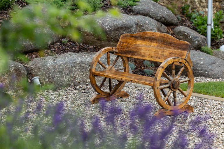 Steingarten mit Kiesbeet und Sitzbank aus Kutschenrädern von Gartengestaltung Hablesreiter.