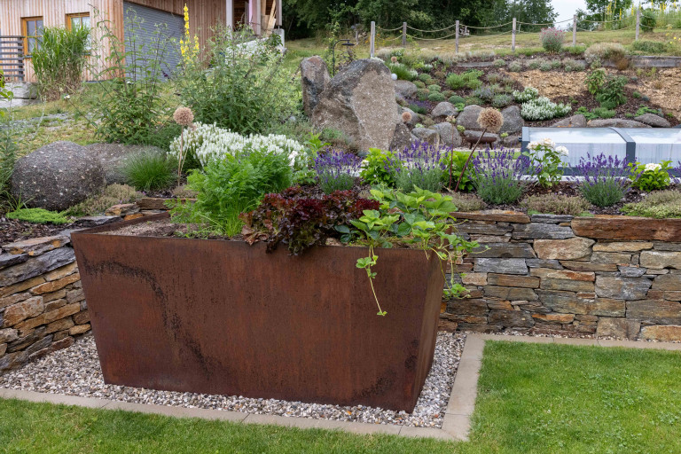 Beet mit Steinmauer und großer Blumentopf aus Eisen in rostiger Optik von Gartengestaltung Hablesreiter.