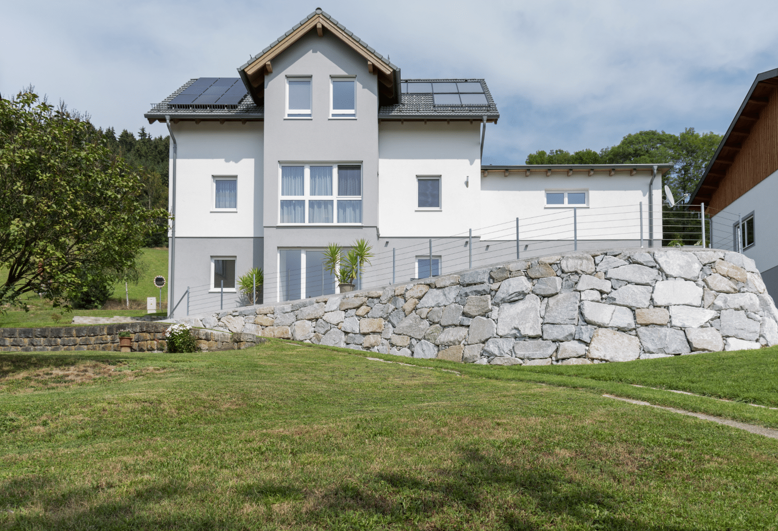 Modernes Fertigteilhaus in Hanglage mit Garten und kleinem, eckigem Erker, erbaut von Hartl Haus.