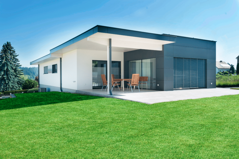 HARTL HAUS Holzindustrie zeigt einen modernen Bungalow in Fertighausbauweise mit Fassadenplatten, Flachdach und Terrasse.